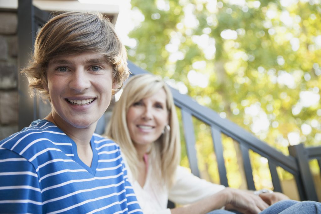 Portrait of happy mother and son sitting on porch