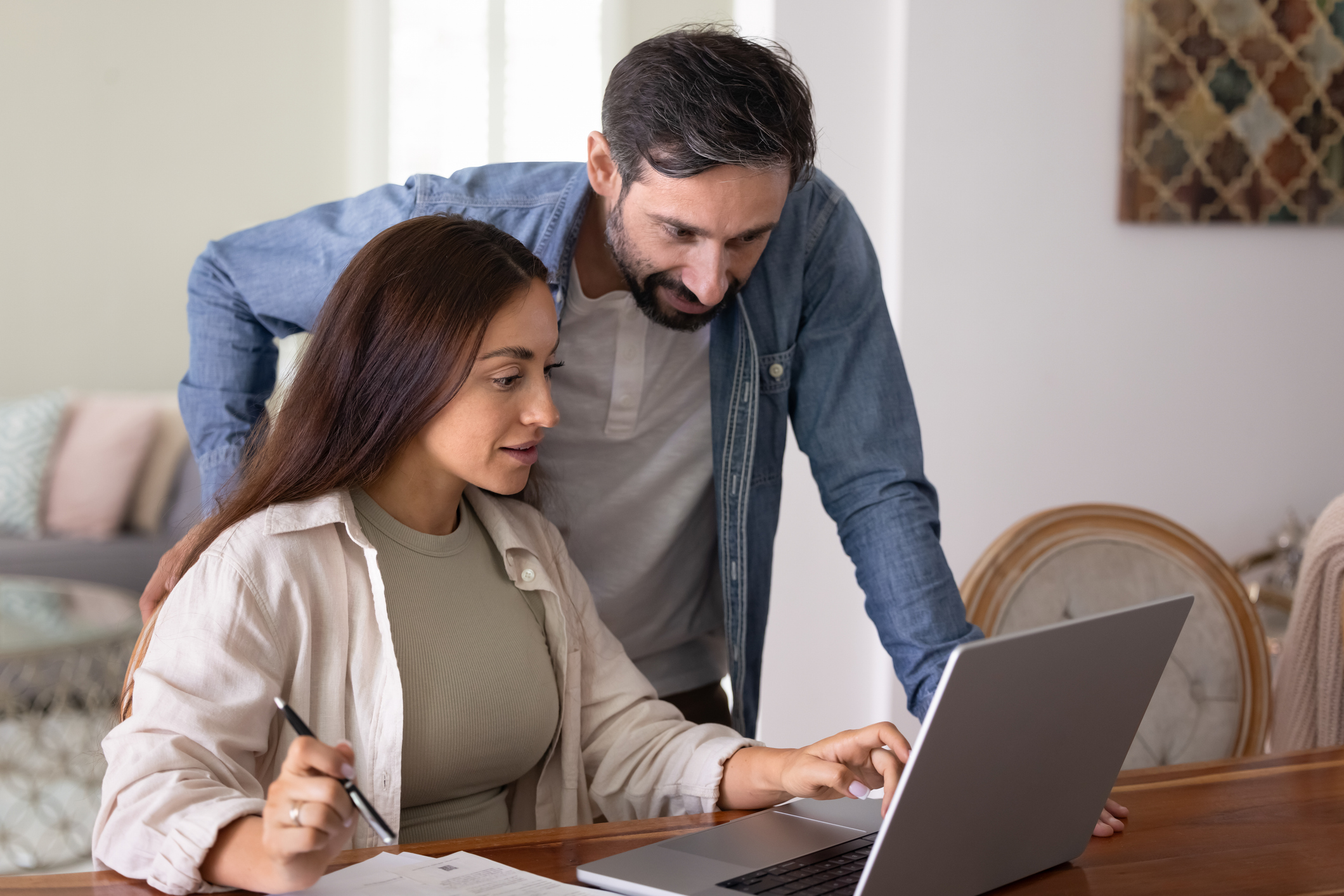 Positive husband and wife using online bank application on laptop