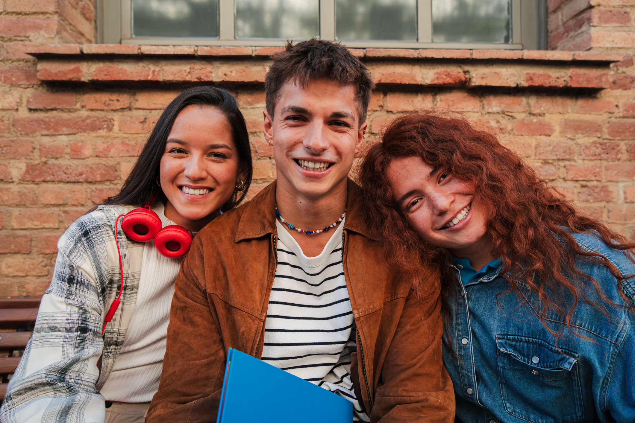 Group of three classmates sitting at university campus looking at the camera